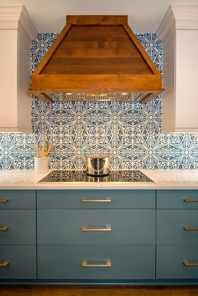 Inredning av ett stort vit vitt kök, med en undermonterad diskho, skåp i shakerstil, blå skåp, bänkskiva i kvarts, blått stänkskydd, stänkskydd i keramik, rostfria vitvaror, mörkt trägolv och brunt golv
