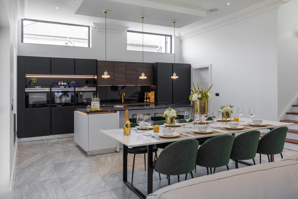 Large contemporary open plan kitchen in Glasgow with flat-panel cabinets, white cabinets, engineered stone countertops, black splashback, glass sheet splashback, black appliances, an island, grey floors and black worktops.