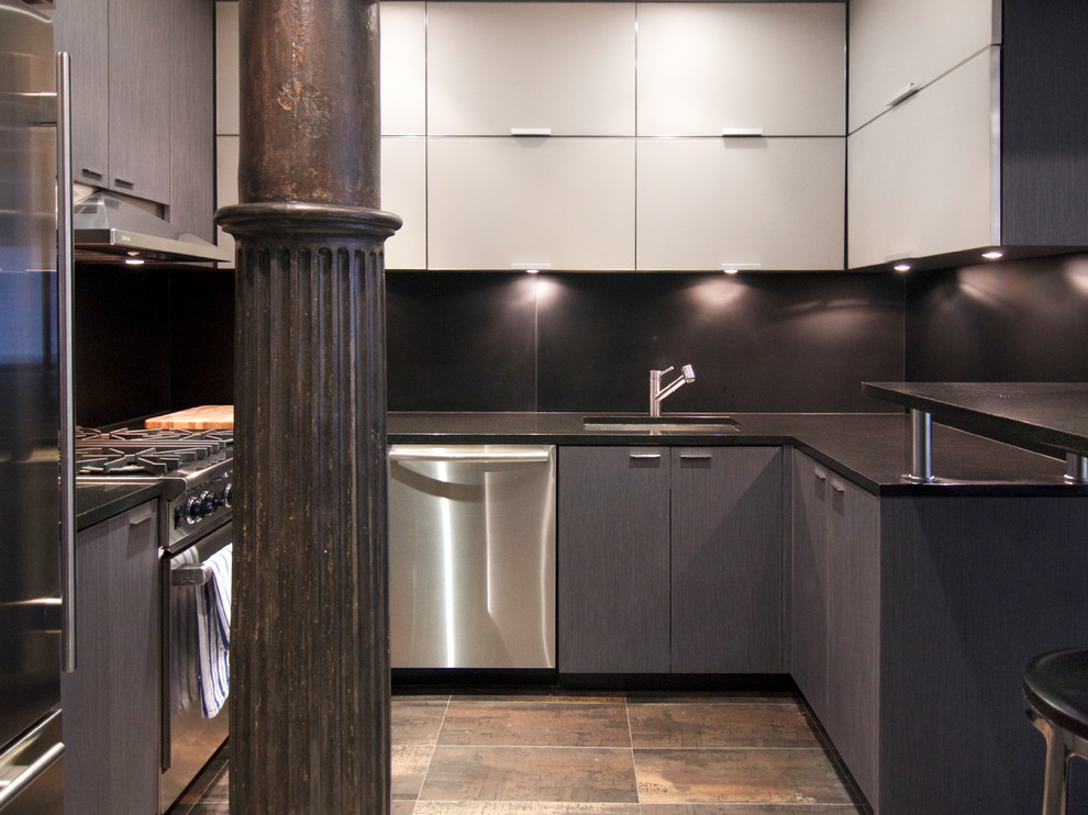 Modern inredning av ett litet svart svart kök, med en undermonterad diskho, släta luckor, grå skåp, granitbänkskiva, svart stänkskydd, stänkskydd i sten, rostfria vitvaror, klinkergolv i porslin, en halv köksö och brunt golv