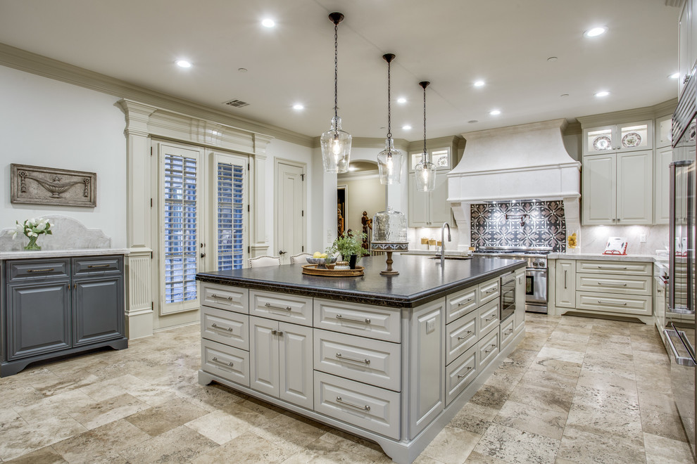 Inspiration for a large timeless l-shaped travertine floor and beige floor eat-in kitchen remodel in Dallas with a farmhouse sink, raised-panel cabinets, beige cabinets, quartzite countertops, beige backsplash, stone slab backsplash, stainless steel appliances and an island
