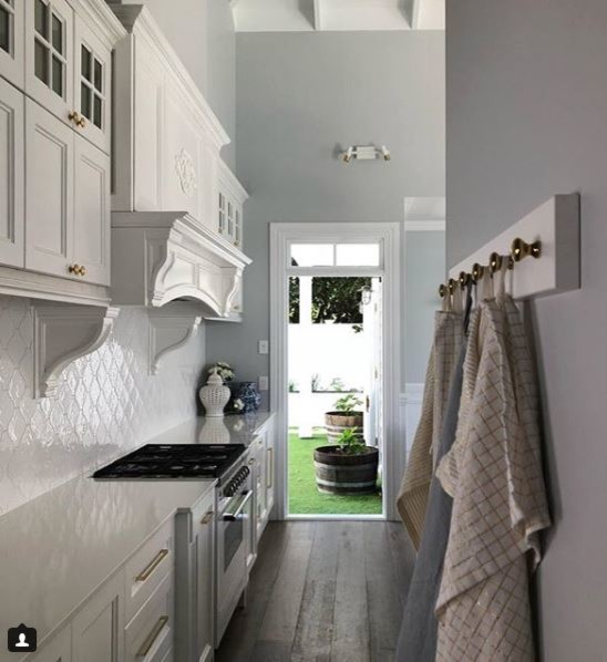 Inspiration for a large beach style open plan kitchen in Hobart with a belfast sink, shaker cabinets, grey cabinets, marble worktops, white splashback, ceramic splashback, white appliances, medium hardwood flooring, an island and brown floors.