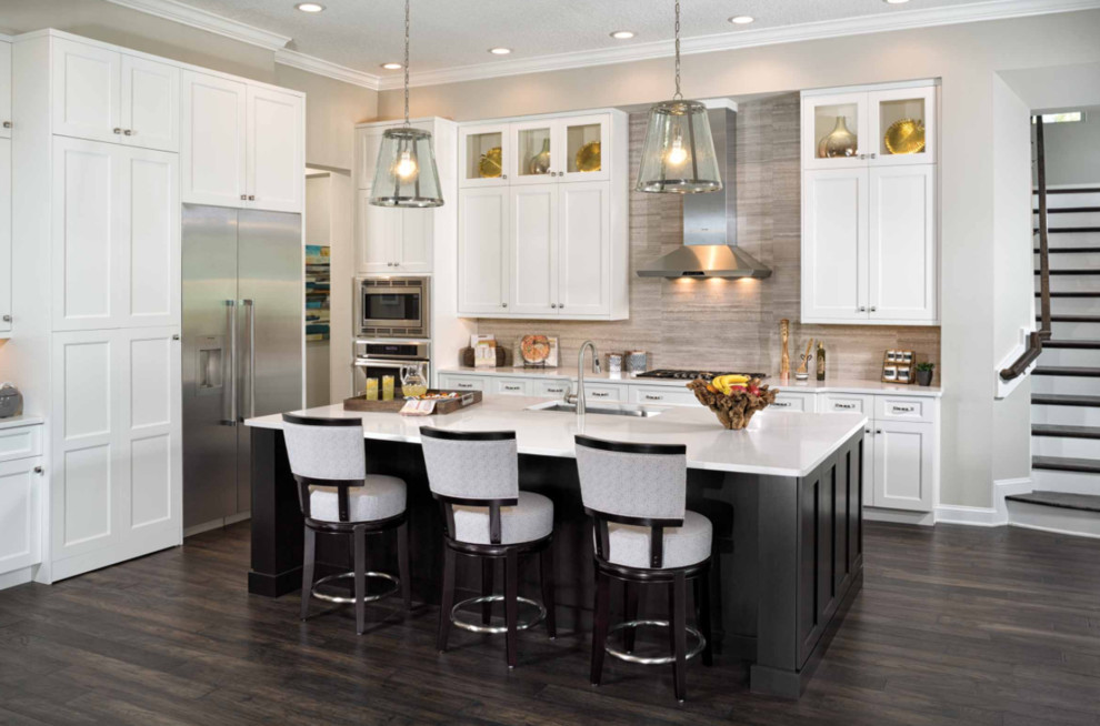Large traditional l-shaped kitchen/diner in San Diego with a submerged sink, shaker cabinets, stainless steel appliances, dark hardwood flooring, an island, composite countertops, beige splashback, stone tiled splashback and brown floors.