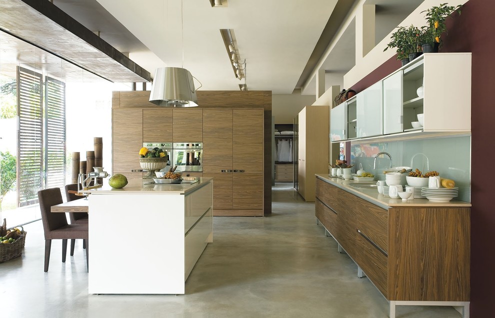 Moderne Küche mit Küchengeräten aus Edelstahl, Kücheninsel, Waschbecken, flächenbündigen Schrankfronten, Glasrückwand und Betonboden in Sonstige