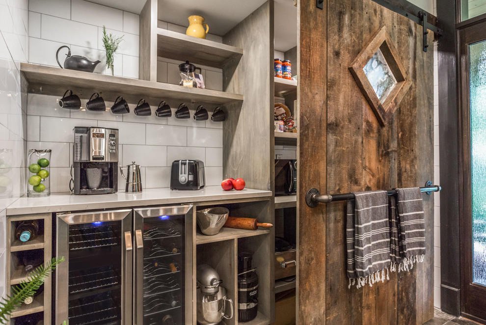 Large rural l-shaped kitchen pantry in Manchester with a submerged sink, flat-panel cabinets, black cabinets, engineered stone countertops, white splashback, porcelain splashback, stainless steel appliances, cement flooring, an island, grey floors and white worktops.