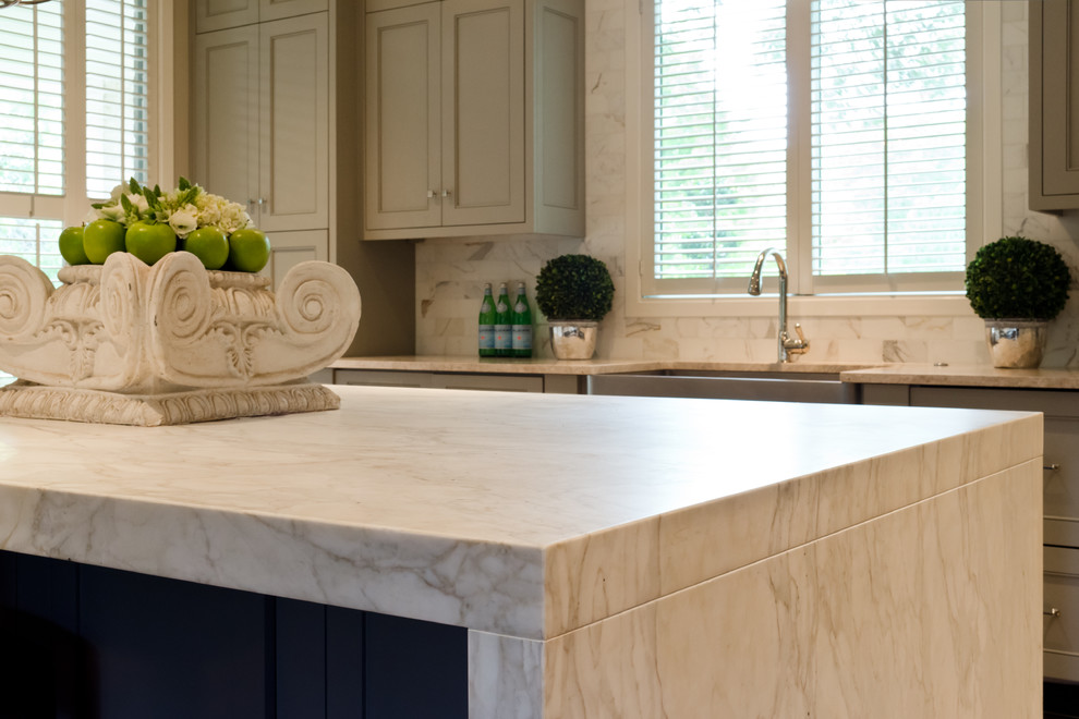 Example of a trendy l-shaped medium tone wood floor kitchen design in Austin with a farmhouse sink, marble countertops, stone tile backsplash, paneled appliances, an island, recessed-panel cabinets, gray cabinets and white backsplash