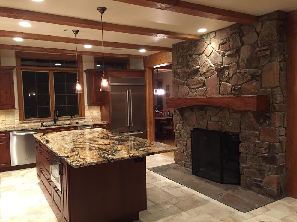 Large arts and crafts l-shaped travertine floor and beige floor enclosed kitchen photo in Denver with an undermount sink, raised-panel cabinets, dark wood cabinets, granite countertops, beige backsplash, stone tile backsplash, stainless steel appliances and an island