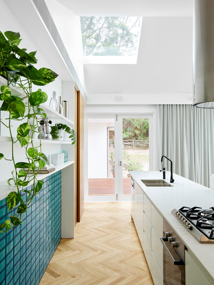 Esempio di una cucina minimalista con lavello a doppia vasca, ante lisce, ante bianche, elettrodomestici in acciaio inossidabile, parquet chiaro, pavimento beige e top bianco