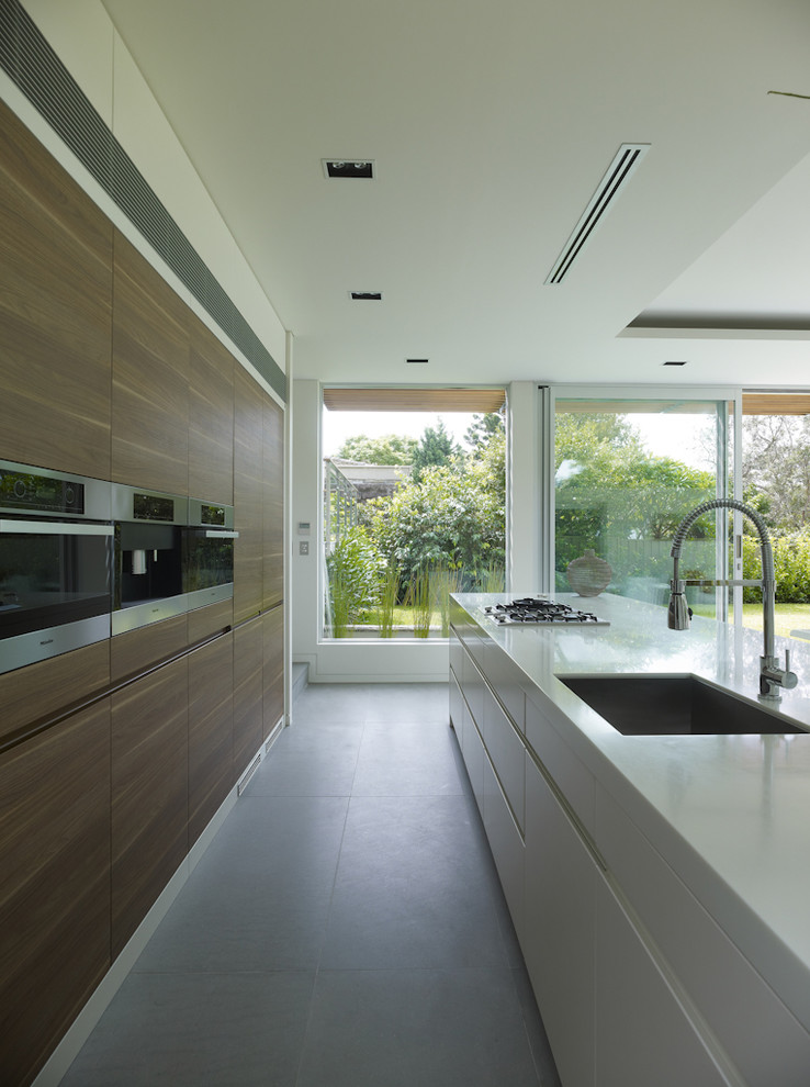 Immagine di una cucina minimal di medie dimensioni con lavello sottopiano, ante lisce, top in quarzo composito, elettrodomestici in acciaio inossidabile e pavimento in ardesia