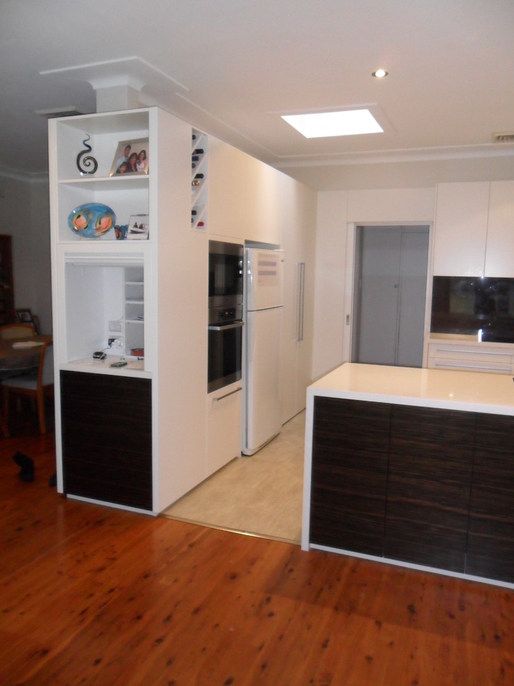 Mittelgroße Moderne Wohnküche in U-Form mit Einbauwaschbecken, weißen Schränken, Quarzwerkstein-Arbeitsplatte, Glasrückwand, Küchengeräten aus Edelstahl, Linoleum und Halbinsel in Sydney
