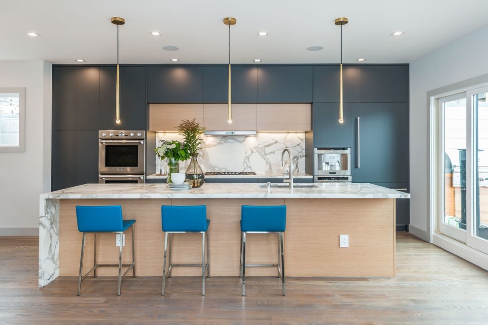 Bild på ett stort funkis kök, med en nedsänkt diskho, släta luckor, marmorbänkskiva, vitt stänkskydd, stänkskydd i marmor, rostfria vitvaror, mellanmörkt trägolv, en köksö, brunt golv och blå skåp