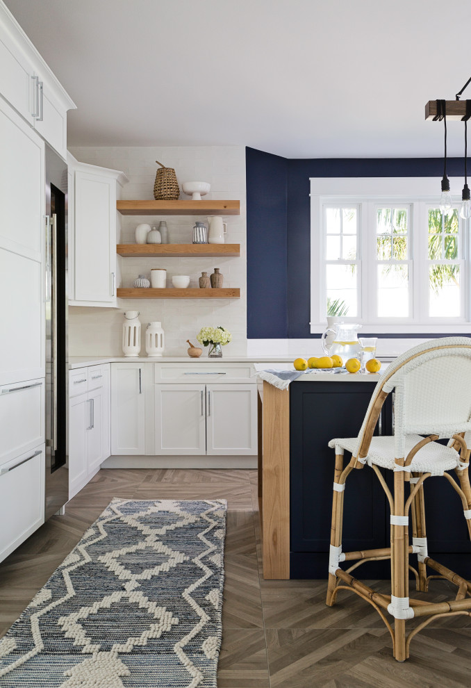Immagine di una grande cucina costiera con ante in stile shaker, ante bianche, elettrodomestici in acciaio inossidabile, pavimento grigio e top bianco