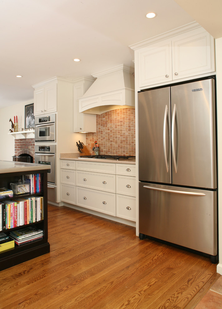 Inspiration for a large contemporary l-shaped medium tone wood floor and brown floor kitchen remodel in DC Metro with an integrated sink, recessed-panel cabinets, white cabinets, stainless steel countertops, brown backsplash, stone tile backsplash, stainless steel appliances and an island