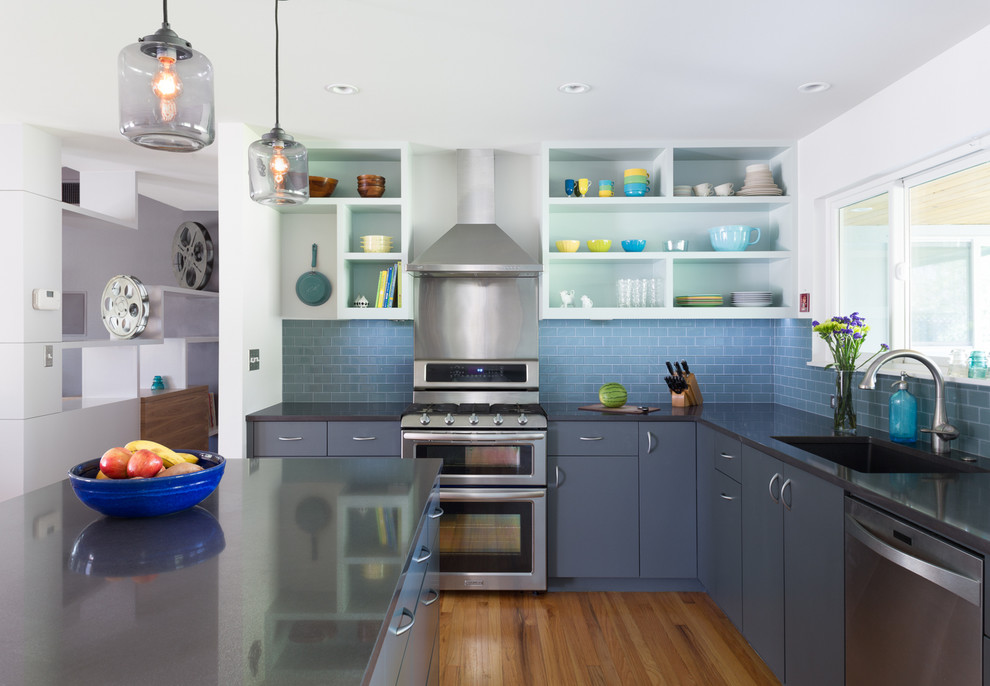 Modern inredning av ett kök, med släta luckor, grå skåp, bänkskiva i kvarts, blått stänkskydd, stänkskydd i glaskakel, mellanmörkt trägolv, en köksö, en undermonterad diskho och rostfria vitvaror