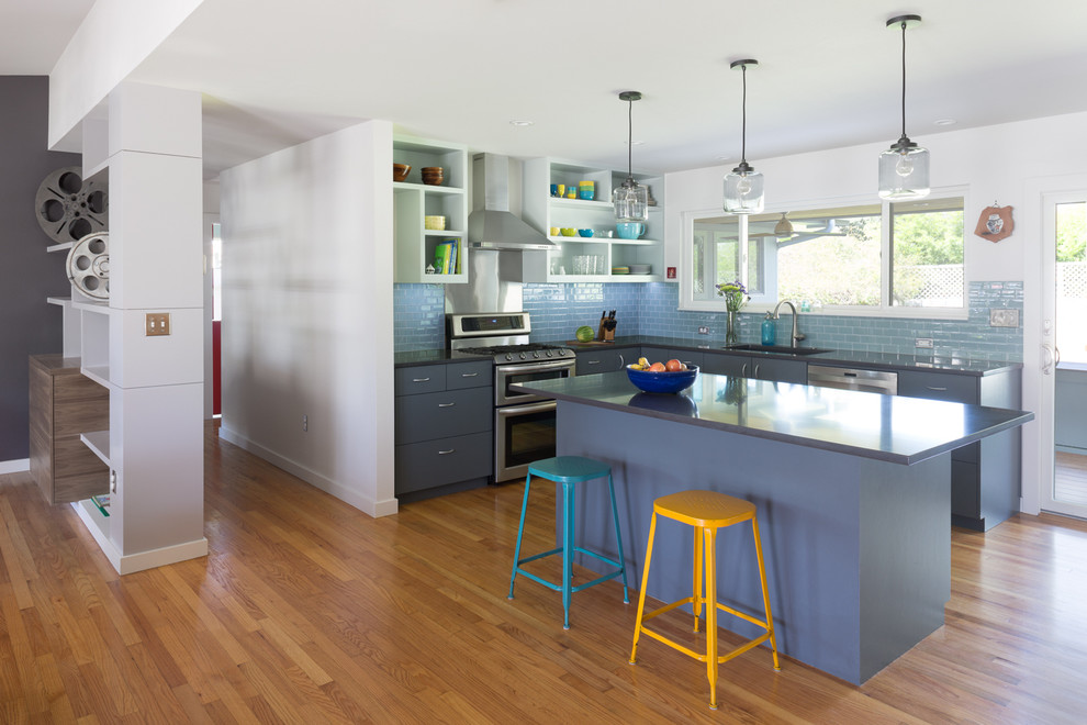 Exempel på ett modernt kök, med en undermonterad diskho, släta luckor, grå skåp, bänkskiva i kvarts, blått stänkskydd, stänkskydd i glaskakel, rostfria vitvaror, mellanmörkt trägolv och en köksö