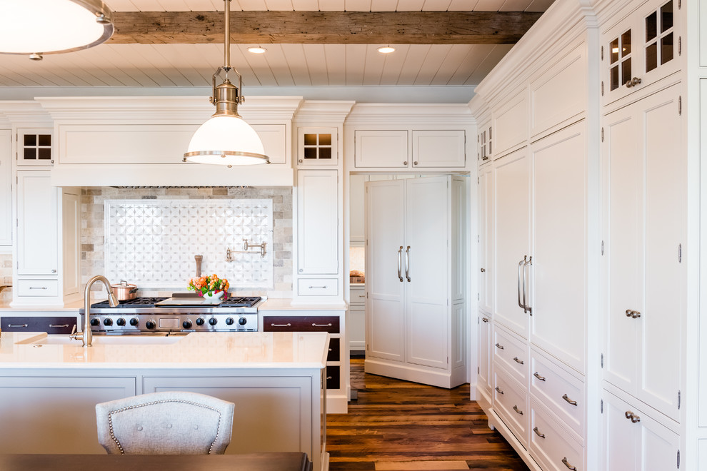 Diseño de cocina tradicional con puertas de armario blancas, salpicadero multicolor, electrodomésticos de acero inoxidable, suelo de madera en tonos medios y armarios con rebordes decorativos
