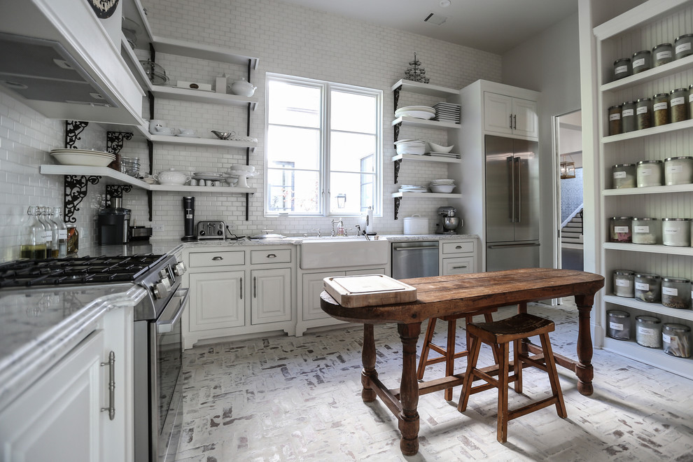 This is an example of a medium sized traditional l-shaped kitchen pantry in Houston with a single-bowl sink, white cabinets, marble worktops, white splashback, stone tiled splashback, stainless steel appliances, brick flooring, no island and flat-panel cabinets.