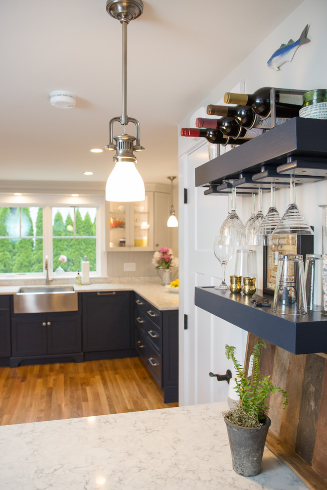 Example of a beach style medium tone wood floor eat-in kitchen design in Boston with a farmhouse sink, shaker cabinets, blue cabinets, quartz countertops, gray backsplash, wood backsplash, stainless steel appliances, a peninsula and white countertops