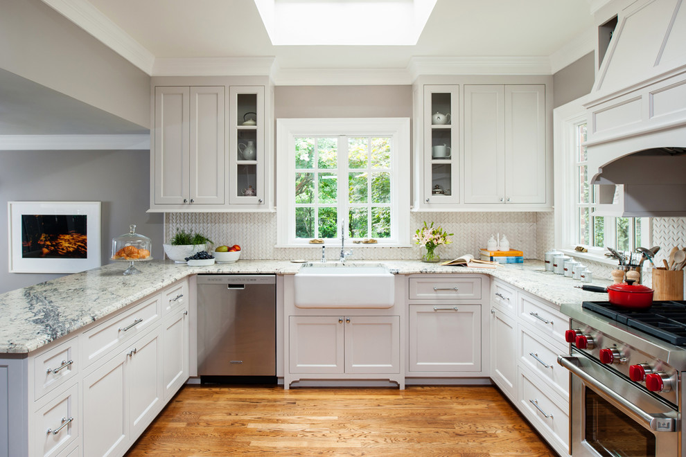 Inspiration for a classic u-shaped kitchen in Richmond with a belfast sink, shaker cabinets, white cabinets, white splashback, stainless steel appliances, medium hardwood flooring, a breakfast bar and marble splashback.