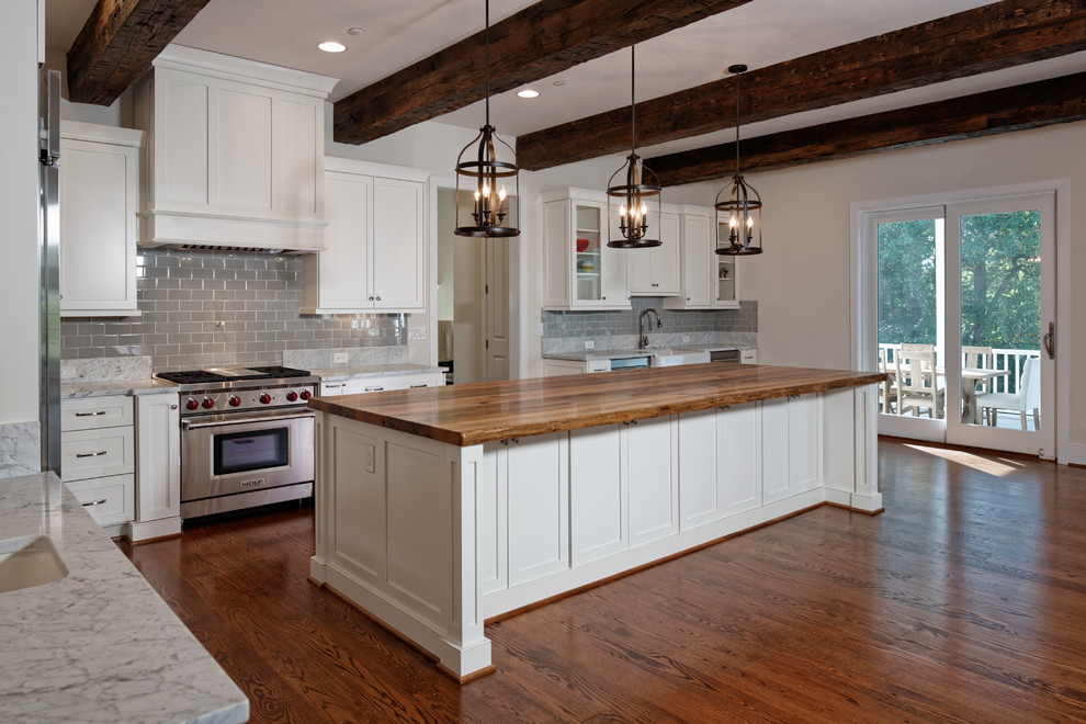 Large trendy l-shaped medium tone wood floor and brown floor kitchen photo in Baltimore with a farmhouse sink, shaker cabinets, white cabinets, marble countertops, gray backsplash, ceramic backsplash, stainless steel appliances, an island and gray countertops