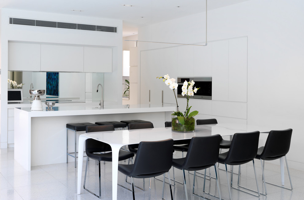 Стильный дизайн: кухня в современном стиле с обеденным столом, плоскими фасадами и белыми фасадами - последний тренд