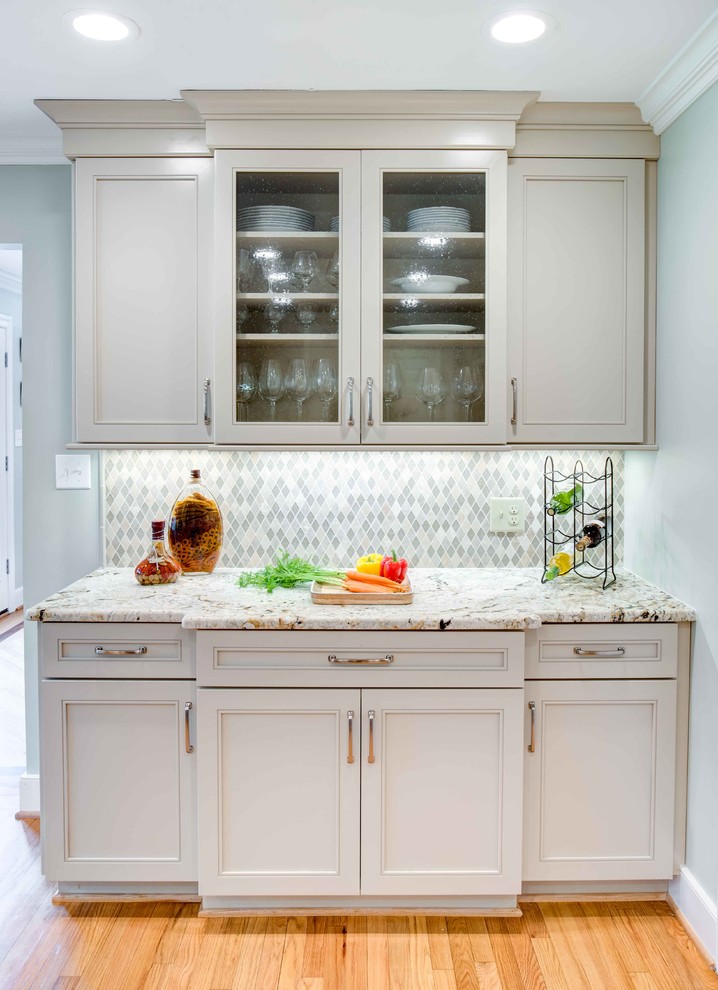Inspiration for a medium sized traditional u-shaped enclosed kitchen in Raleigh with a submerged sink, recessed-panel cabinets, white cabinets, granite worktops, white splashback, glass tiled splashback, stainless steel appliances, medium hardwood flooring, an island and brown floors.
