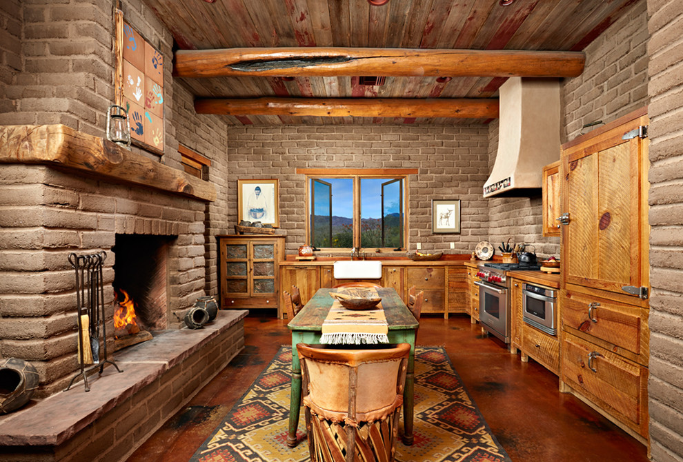 Example of a large southwest u-shaped concrete floor eat-in kitchen design in Phoenix with a farmhouse sink, medium tone wood cabinets, stainless steel appliances, an island, wood countertops, raised-panel cabinets, beige backsplash and stone tile backsplash