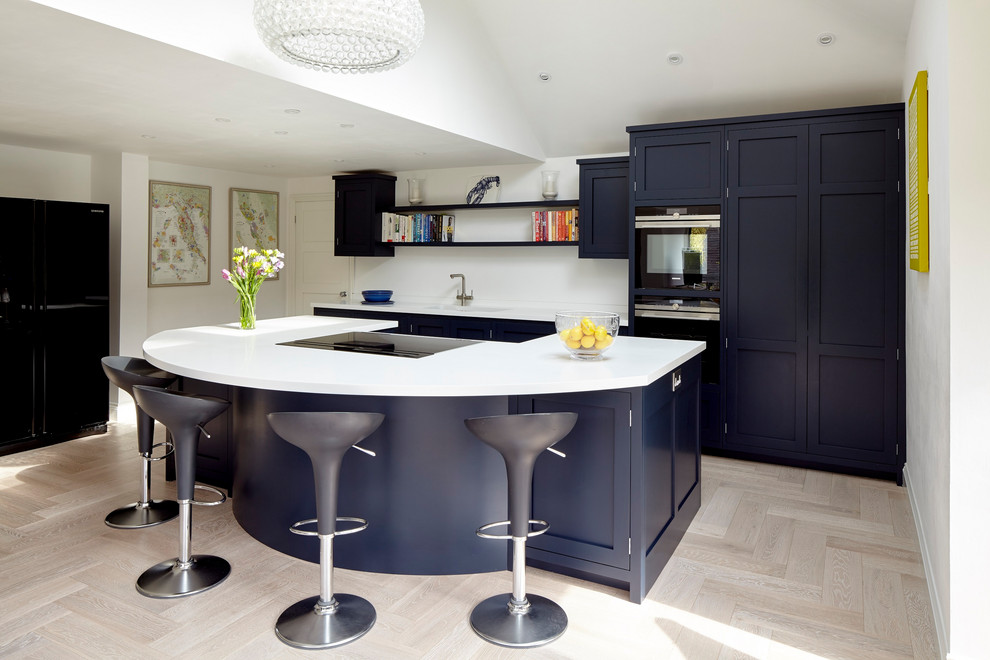 Example of a mid-sized trendy single-wall light wood floor open concept kitchen design in London with an undermount sink, shaker cabinets, blue cabinets, solid surface countertops, an island and white countertops