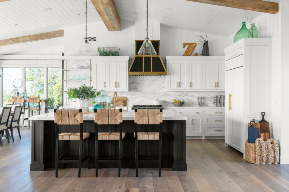 Bild på ett vintage vit vitt l-kök, med skåp i shakerstil, vita skåp, vitt stänkskydd, stänkskydd i sten, integrerade vitvaror, mörkt trägolv, en köksö och brunt golv