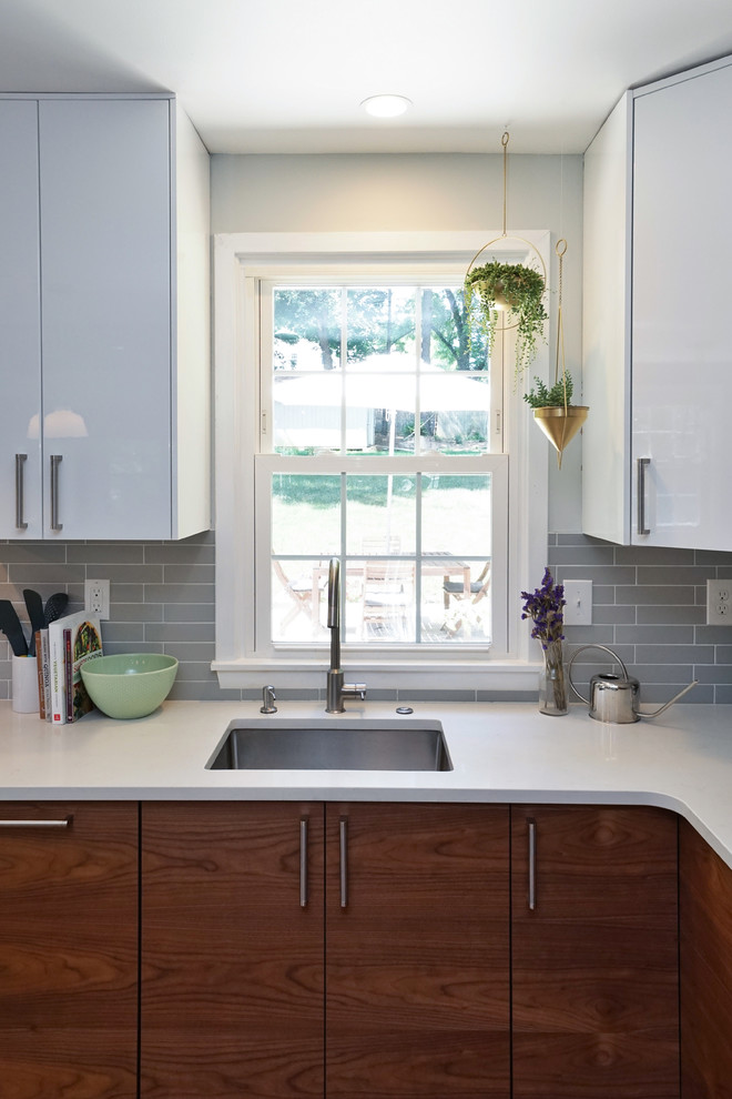 Exempel på ett mellanstort modernt kök, med en undermonterad diskho, bänkskiva i kvarts, grått stänkskydd, stänkskydd i keramik, rostfria vitvaror, en köksö, släta luckor, vita skåp, mellanmörkt trägolv och brunt golv