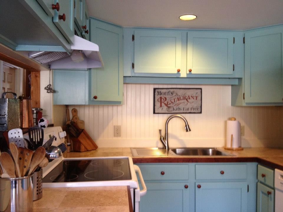 Foto på ett litet lantligt kök, med en nedsänkt diskho, skåp i shakerstil, blå skåp, kaklad bänkskiva, vitt stänkskydd, stänkskydd i trä och vita vitvaror