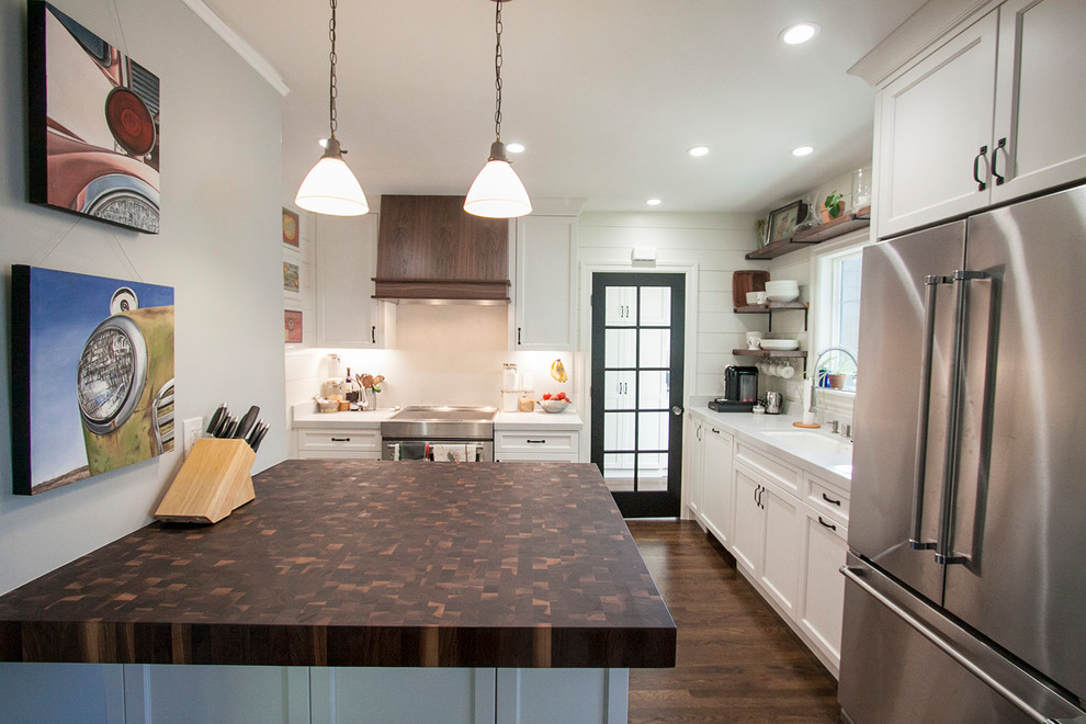 Bild på ett mellanstort amerikanskt kök, med en undermonterad diskho, luckor med infälld panel, vita skåp, bänkskiva i kvarts, vitt stänkskydd, stänkskydd i sten, rostfria vitvaror, mellanmörkt trägolv, en köksö och brunt golv