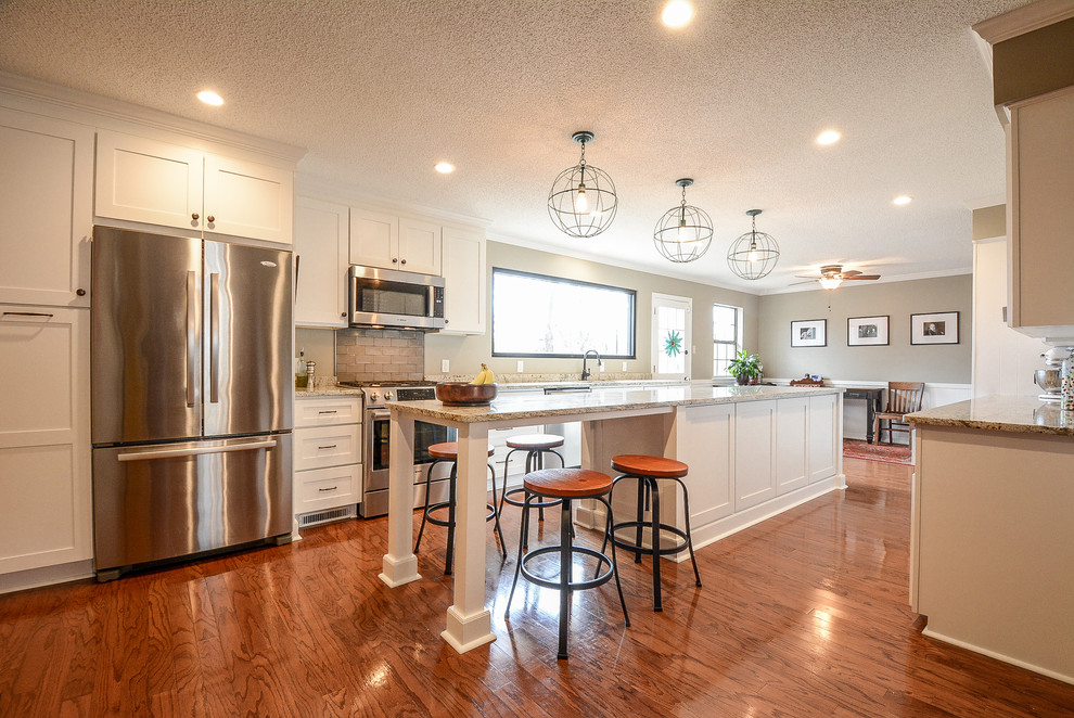 Inspiration for a large transitional galley medium tone wood floor and brown floor eat-in kitchen remodel in Little Rock with a double-bowl sink, shaker cabinets, white cabinets, granite countertops, green backsplash, stainless steel appliances and an island