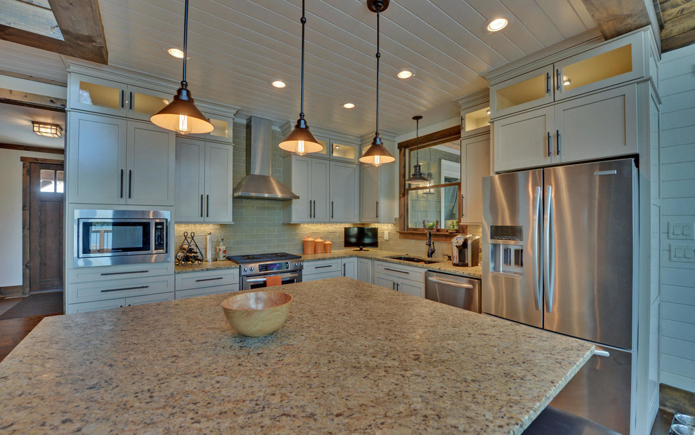 This is an example of a large traditional l-shaped kitchen/diner in Atlanta with a submerged sink, shaker cabinets, white cabinets, granite worktops, beige splashback, metro tiled splashback, stainless steel appliances, dark hardwood flooring, an island and brown floors.