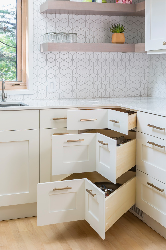 Photo of a medium sized scandi u-shaped kitchen in Minneapolis with a double-bowl sink, flat-panel cabinets, white cabinets, white splashback, ceramic splashback, stainless steel appliances, light hardwood flooring, no island, yellow floors and white worktops.