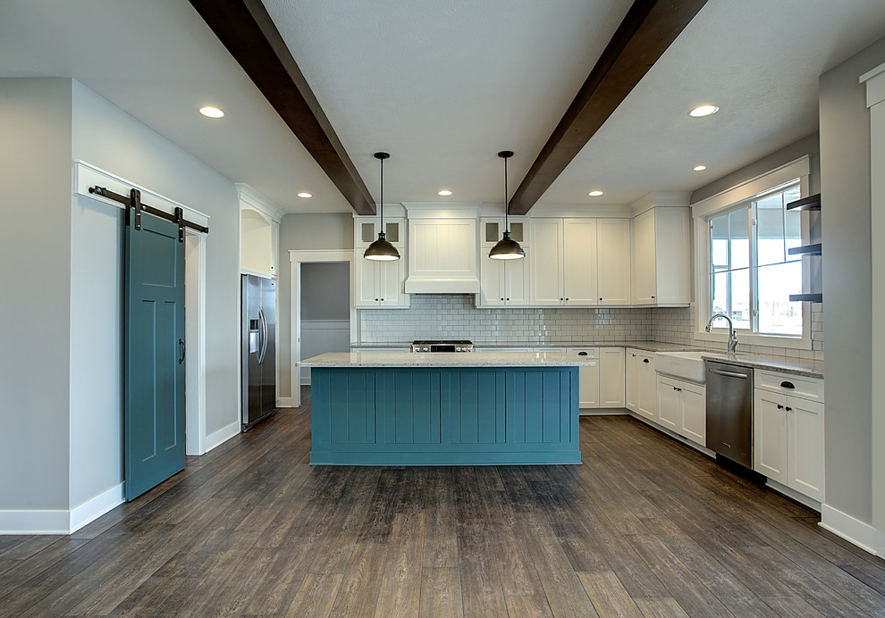 Idée de décoration pour une arrière-cuisine craftsman en U de taille moyenne avec un évier de ferme, un placard à porte shaker, des portes de placard jaunes, un plan de travail en granite, une crédence jaune, une crédence en céramique, un électroménager en acier inoxydable, un sol en bois brun, îlot et un sol marron.