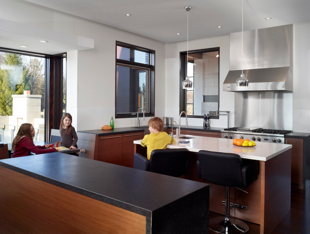 Offene Moderne Küche in U-Form mit Unterbauwaschbecken, flächenbündigen Schrankfronten, hellbraunen Holzschränken, Küchengeräten aus Edelstahl, dunklem Holzboden, zwei Kücheninseln und braunem Boden in Toronto