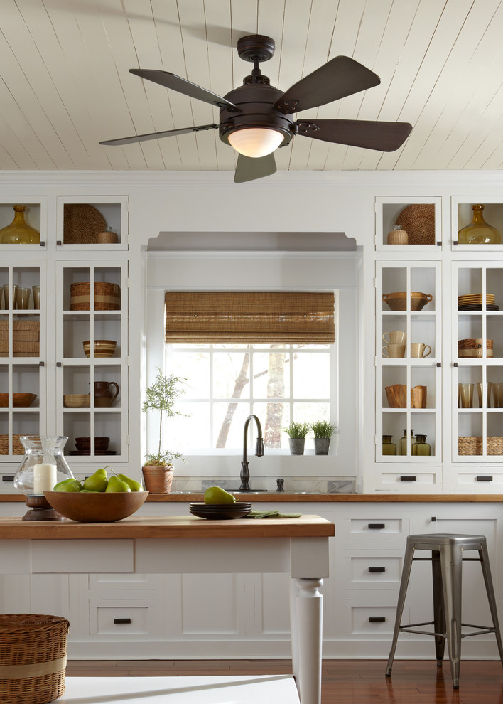 Inspiration for a small rustic galley medium tone wood floor enclosed kitchen remodel in New York with an undermount sink, open cabinets, white cabinets, wood countertops, white backsplash, cement tile backsplash, stainless steel appliances and an island