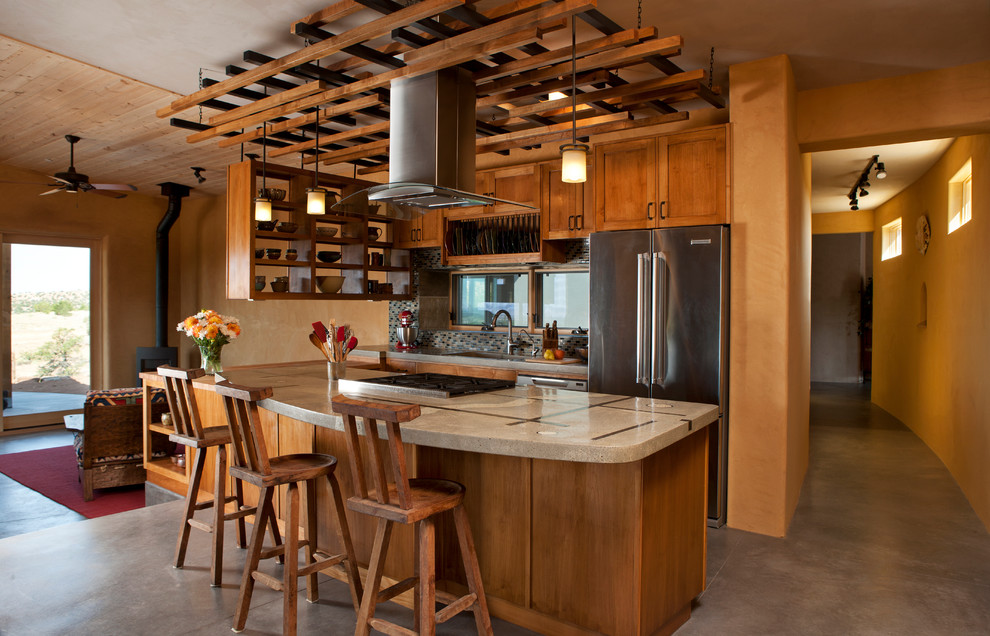アルバカーキにあるサンタフェスタイルのおしゃれなII型キッチン (コンクリートカウンター、シェーカースタイル扉のキャビネット、中間色木目調キャビネット、シルバーの調理設備) の写真