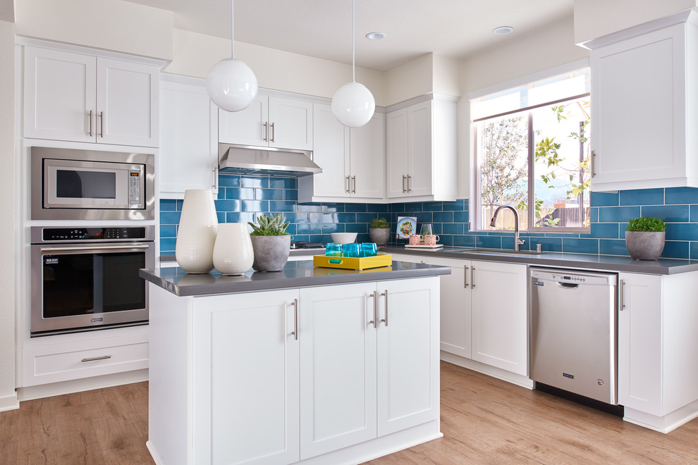 Classic l-shaped kitchen in Orange County with a submerged sink, shaker cabinets, white cabinets, blue splashback, stainless steel appliances, medium hardwood flooring and an island.