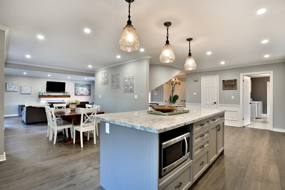 Inspiration for a mid-sized modern l-shaped medium tone wood floor eat-in kitchen remodel with an undermount sink, shaker cabinets, white cabinets, granite countertops, gray backsplash, stainless steel appliances and an island