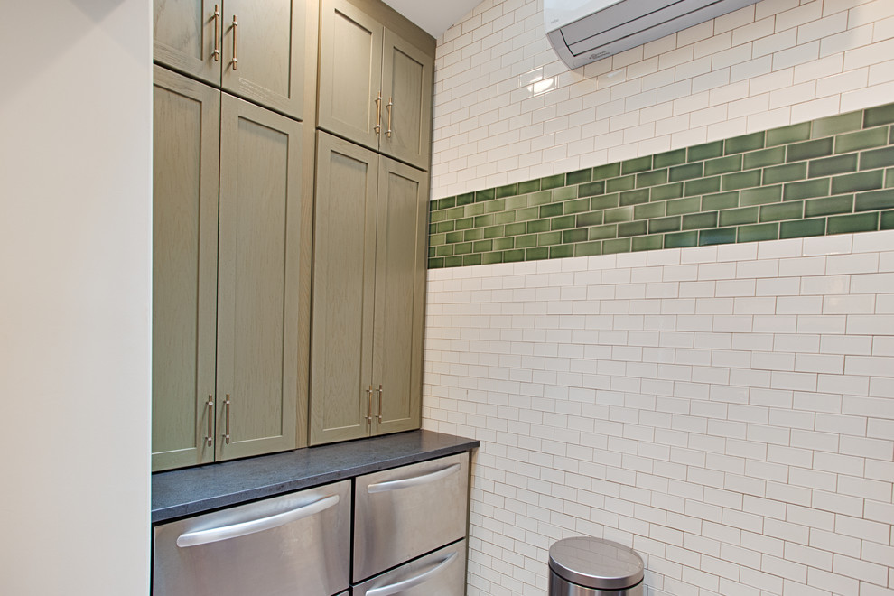 Modern inredning av ett avskilt, mellanstort l-kök, med en undermonterad diskho, släta luckor, gröna skåp, grönt stänkskydd, stänkskydd i tunnelbanekakel, rostfria vitvaror, betonggolv och granitbänkskiva