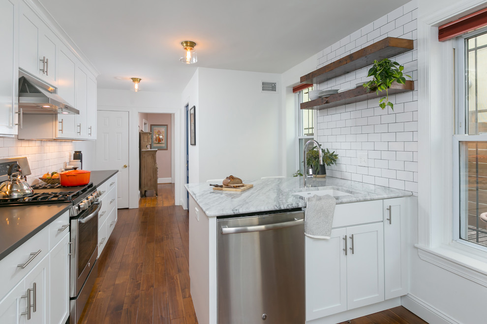 Exempel på ett avskilt, mellanstort modernt l-kök, med en undermonterad diskho, skåp i shakerstil, vita skåp, bänkskiva i kvartsit, vitt stänkskydd, stänkskydd i tunnelbanekakel, rostfria vitvaror, mellanmörkt trägolv, en halv köksö och brunt golv
