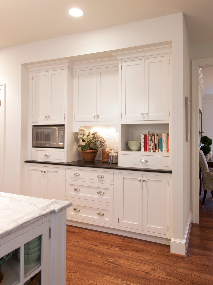 Foto de cocinas en U clásico con puertas de armario blancas, encimera de granito, electrodomésticos de acero inoxidable y una isla