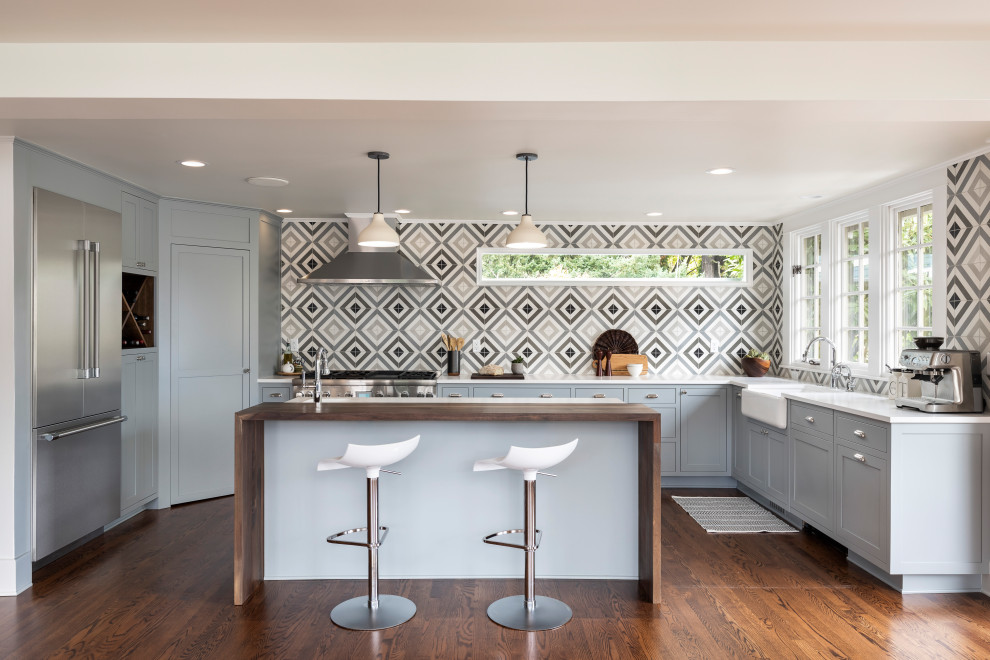 Kitchen - contemporary l-shaped dark wood floor and brown floor kitchen idea in Portland with a farmhouse sink, shaker cabinets, gray cabinets, gray backsplash, stainless steel appliances, an island and white countertops
