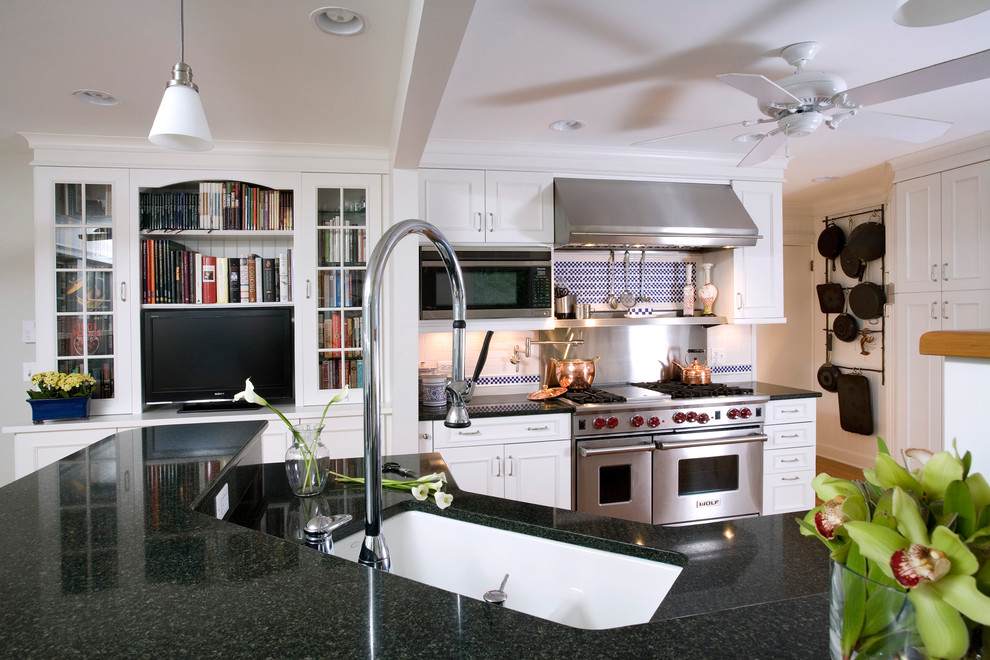 Exempel på ett stort, avskilt klassiskt l-kök, med en undermonterad diskho, luckor med infälld panel, vita skåp, granitbänkskiva, vitt stänkskydd, stänkskydd i keramik, rostfria vitvaror, ljust trägolv och en köksö