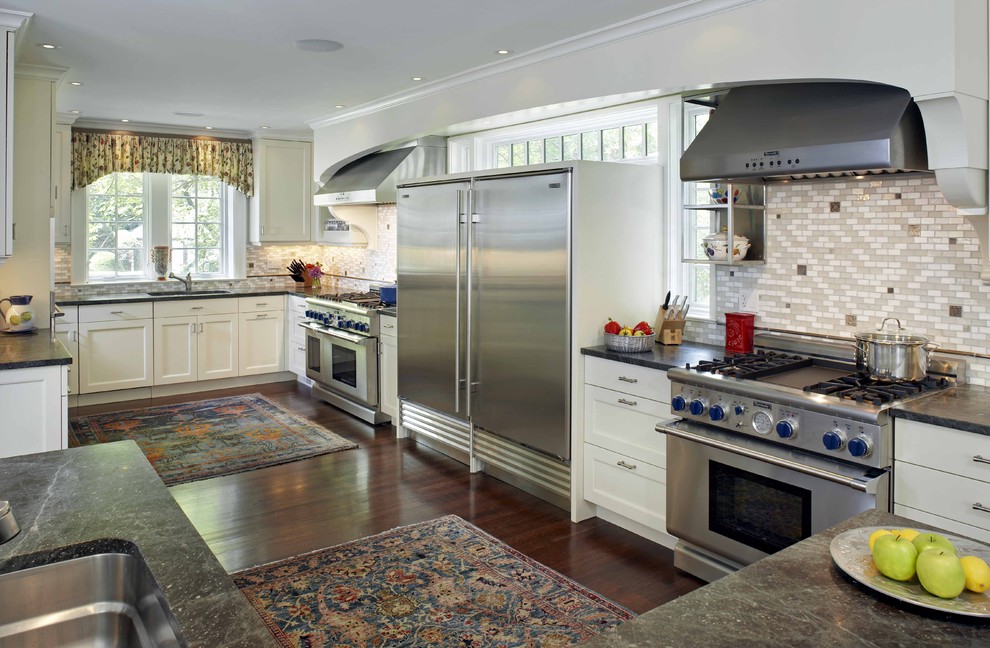 Exemple d'une cuisine chic en U avec un plan de travail en stéatite, un électroménager en acier inoxydable, des portes de placard blanches et une crédence multicolore.