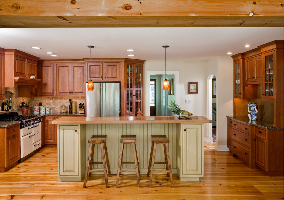 Cette photo montre une cuisine chic en U et bois brun avec un placard avec porte à panneau surélevé, une crédence beige et un électroménager en acier inoxydable.