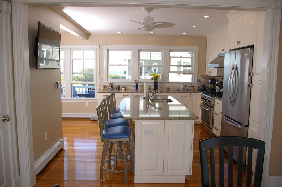 Immagine di una cucina chic con lavello sottopiano, ante bianche, top in granito, paraspruzzi grigio e elettrodomestici in acciaio inossidabile
