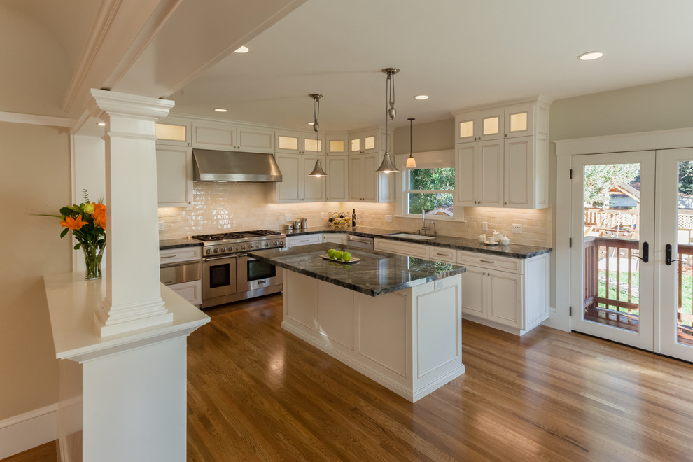 Example of an arts and crafts u-shaped medium tone wood floor eat-in kitchen design in San Francisco with white cabinets, stainless steel appliances, recessed-panel cabinets and an island