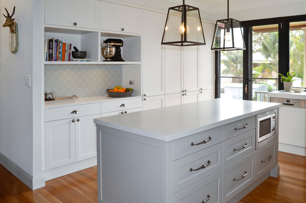 Inspiration for a medium sized classic u-shaped kitchen/diner in Newcastle - Maitland with a double-bowl sink, shaker cabinets, white cabinets, engineered stone countertops, multi-coloured splashback, glass tiled splashback, stainless steel appliances, light hardwood flooring and an island.